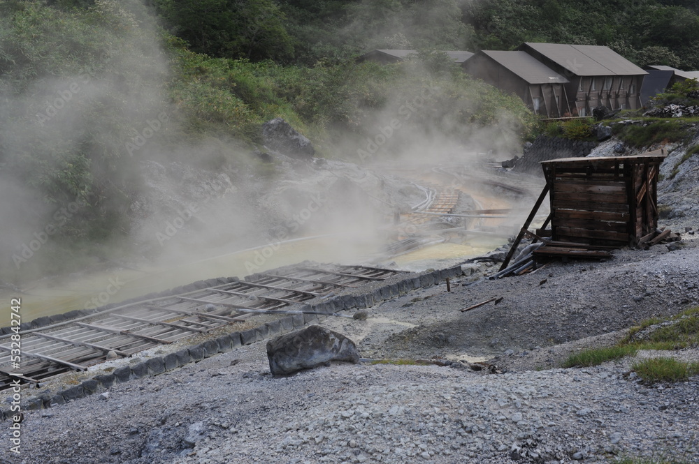 Sulphurous mountain valley with hot spring stream and steam at Tamagawa ...