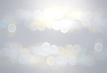 Silver flares shining blur background for winter holidays design. Airy grey backdrop decorated lights bokeh effect .