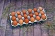 Braune Bio Eier in einer Eierschachtel auf rustikalem Holz,