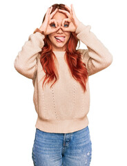 Sticker - Young redhead woman wearing casual winter sweater doing ok gesture like binoculars sticking tongue out, eyes looking through fingers. crazy expression.