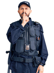 Poster - Young handsome man wearing police uniform asking to be quiet with finger on lips. silence and secret concept.