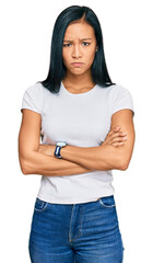 Poster - Beautiful hispanic woman wearing casual white tshirt skeptic and nervous, disapproving expression on face with crossed arms. negative person.