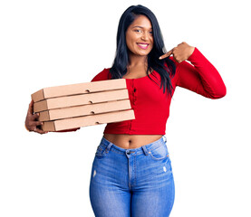 Canvas Print - Hispanic woman with long hair holding delivery pizza box pointing finger to one self smiling happy and proud