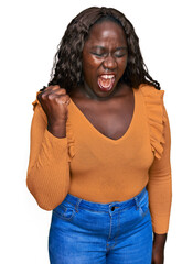 Sticker - Young african woman wearing casual clothes angry and mad raising fist frustrated and furious while shouting with anger. rage and aggressive concept.