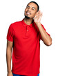 © Krakenimages.com - Young african american man wearing casual polo smiling with hand over ear listening and hearing to rumor or gossip. deafness concept.