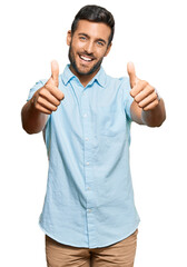 Wall Mural - Handsome hispanic man wearing casual clothes approving doing positive gesture with hand, thumbs up smiling and happy for success. winner gesture.