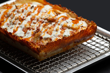 detroit pizza on an iron tray on a dark background.