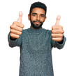 © Krakenimages.com - Young african american man wearing casual clothes approving doing positive gesture with hand, thumbs up smiling and happy for success. winner gesture.
