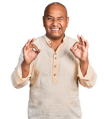 Hispanic middle age man doing ok gesture with hand winking looking at the camera with sexy expression, cheerful and happy face.