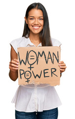 Canvas Print - Beautiful hispanic woman holding woman power banner looking positive and happy standing and smiling with a confident smile showing teeth