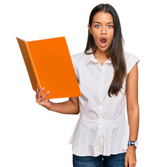 Canvas Print - Beautiful hispanic woman reading book scared and amazed with open mouth for surprise, disbelief face