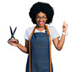 © Krakenimages.com - Young african american woman dressmaker designer wearing atelier apron holding scissors screaming proud, celebrating victory and success very excited with raised arm
