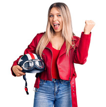 Young Beautiful Blonde Woman Holding Motorcycle Helmet Screaming Proud, Celebrating Victory And Success Very Excited With Raised Arms