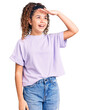 © Krakenimages.com - Beautiful kid girl with curly hair wearing casual clothes very happy and smiling looking far away with hand over head. searching concept.