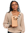 © Krakenimages.com - African american woman holding gift thinking attitude and sober expression looking self confident