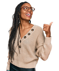 Wall Mural - African american woman wearing casual clothes smiling with happy face looking and pointing to the side with thumb up.