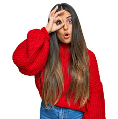 Wall Mural - Beautiful hispanic woman wearing casual clothes doing ok gesture shocked with surprised face, eye looking through fingers. unbelieving expression.