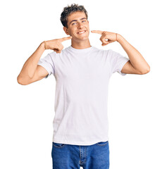 Young handsome man wearing casual white tshirt smiling cheerful showing and pointing with fingers teeth and mouth. dental health concept.