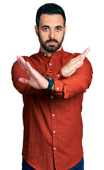 Wall Mural - Young hispanic man with beard wearing casual shirt rejection expression crossing arms and palms doing negative sign, angry face