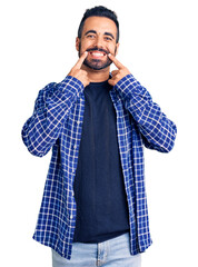 Canvas Print - Young hispanic man wearing casual clothes smiling with open mouth, fingers pointing and forcing cheerful smile