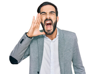 Wall Mural - Young hispanic man wearing business clothes shouting and screaming loud to side with hand on mouth. communication concept.