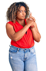 Wall Mural - Young african american plus size woman wearing casual style with sleeveless shirt holding symbolic gun with hand gesture, playing killing shooting weapons, angry face