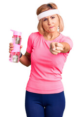 Wall Mural - Young blonde woman wearing sportswear holding water bottle annoyed and frustrated shouting with anger, yelling crazy with anger and hand raised