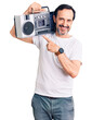 © Krakenimages.com - Middle age handsome man listening to music using vintage boombox smiling happy pointing with hand and finger