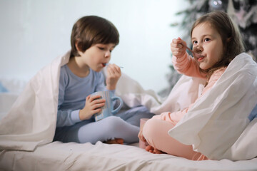 Wall Mural - A family with children having fun on the bed under the covers during the Christmas holidays.