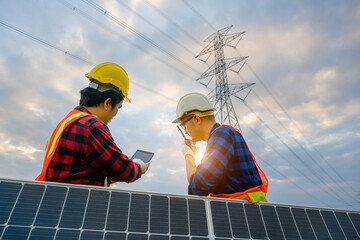 A team of two male electrical engineers using tablets to watch power stations and solar photovoltaic renewable energy panels. To plan the production of electricity at high voltage poles