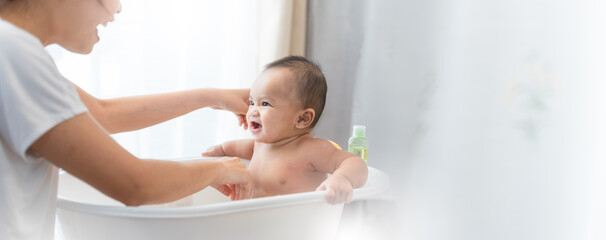 Wall Mural - young Asian mother is Bathing with her newborn baby In Bathtub at home.Concept of newborn,baby,parenthood,motherhood,childhood,New life,maternity,love,new family member
