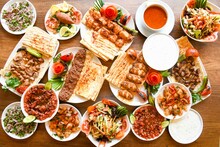 Traditional Turkish Cuisine. Pizza, Pita, Pidesi, Sucuk, Hummus, Kebab. Many Dishes On The Table. Serving Dishes In Restaurant. Background Image. Top View, Flat Lay