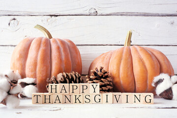 Poster - Happy Thanksgiving greeting on wooden blocks against a white wood background with muted orange pumpkins and autumn decor