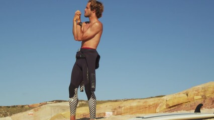 Wall Mural - Athletic man stretching arms before surfing and training at the beach