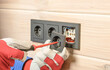 installation of a block of three black sockets on a wooden wall