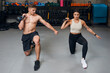 Male personal trainer instructing female with kettlebell routine in the gym