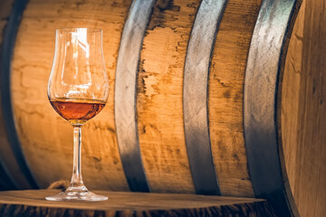 Close up of white port wine in wineglass in front of oak barrel