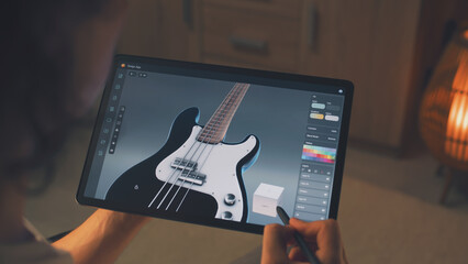 Poster - Man working at home remotely and creating 3D prototype of guitar in professional program using digital tablet computer and stylus