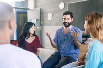 Young friendly teacher listening and talking with teenager students - Group discussion in Education