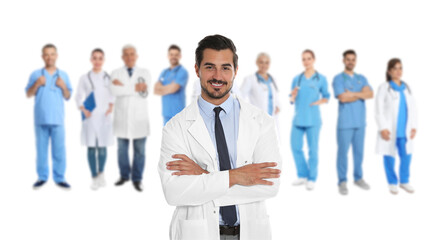 Wall Mural - Handsome young doctor and blurred view of medical staff on white background. Banner design