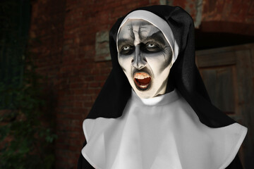 Wall Mural - Portrait of scary devilish nun outdoors, space for text. Halloween party look