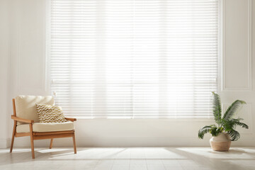 Poster - Soft armchair and houseplant near large window with blinds in spacious room. Interior design