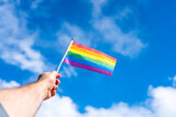 Fototapeta Tęcza - LGBT flag in the sky in a man's hand