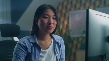 Poster - Asian woman sitting at the table and looking at screen of personal computer while surfing the internet in spare time or working remotely from home