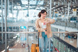 Happy attractive asian woman looking at her wrist watch while waiting in airport terminal, copy space, Tourist journey trip concept