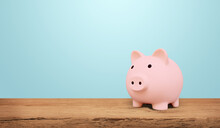 Piggy Bank On A Wooden Table With Blue Background. Saving Money And Invest Concept.