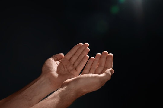 Man reaching hands to light in darkness, closeup