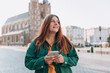 © mdyn - Beautiful stylish woman walking on Market Square in Krakow on autumn day and holding mobile phone. Phone Communication. Urban lifestyle concept. Check social networks, send sms.