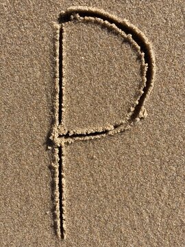 On the beach in the sand is carved the letter P