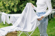 woman hanging clean clothes on drying rack outside